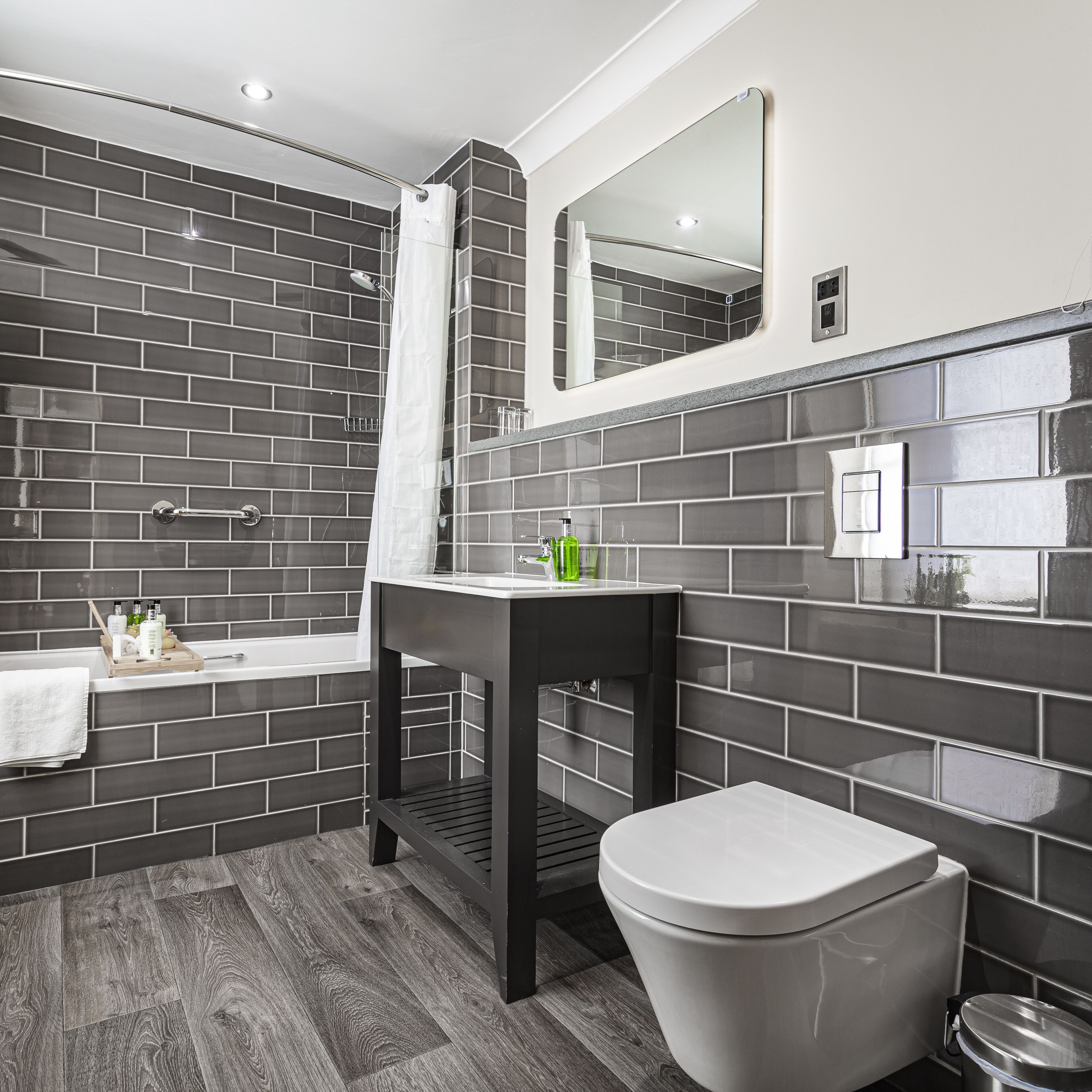 A modern bathroom with a shower, toilet, and sink.