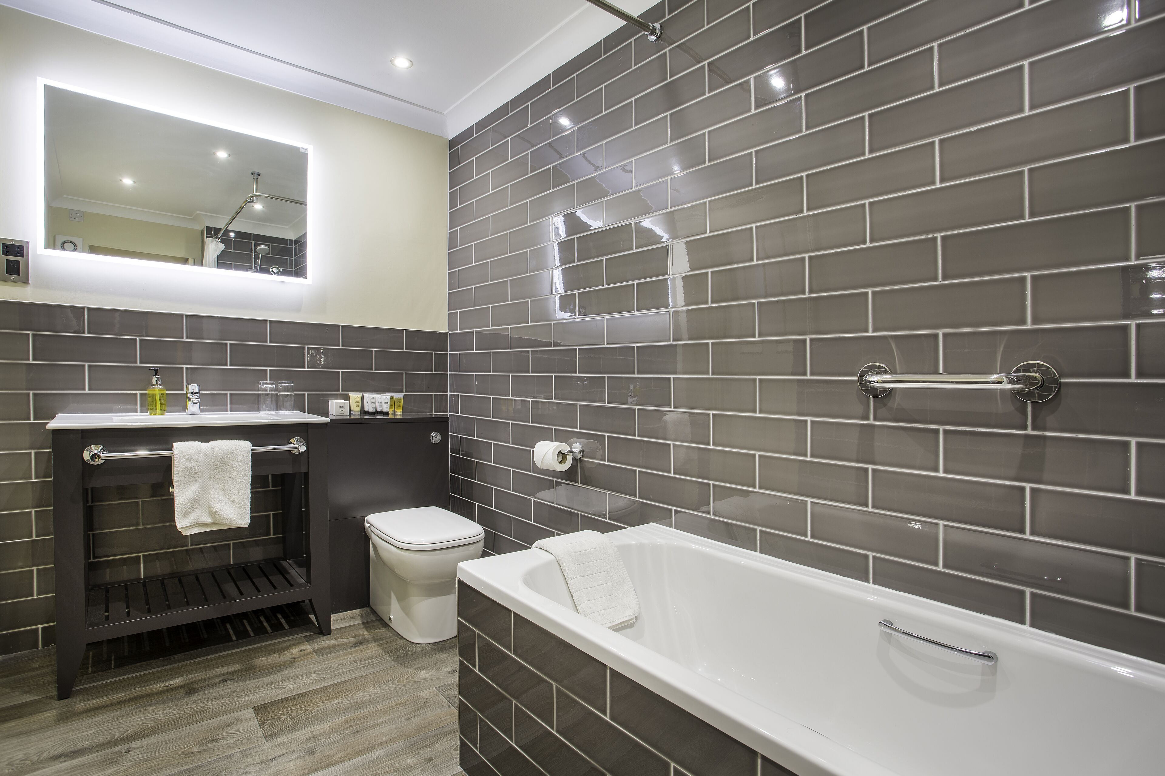A modern bathroom with a bathtub, toilet, and vanity.