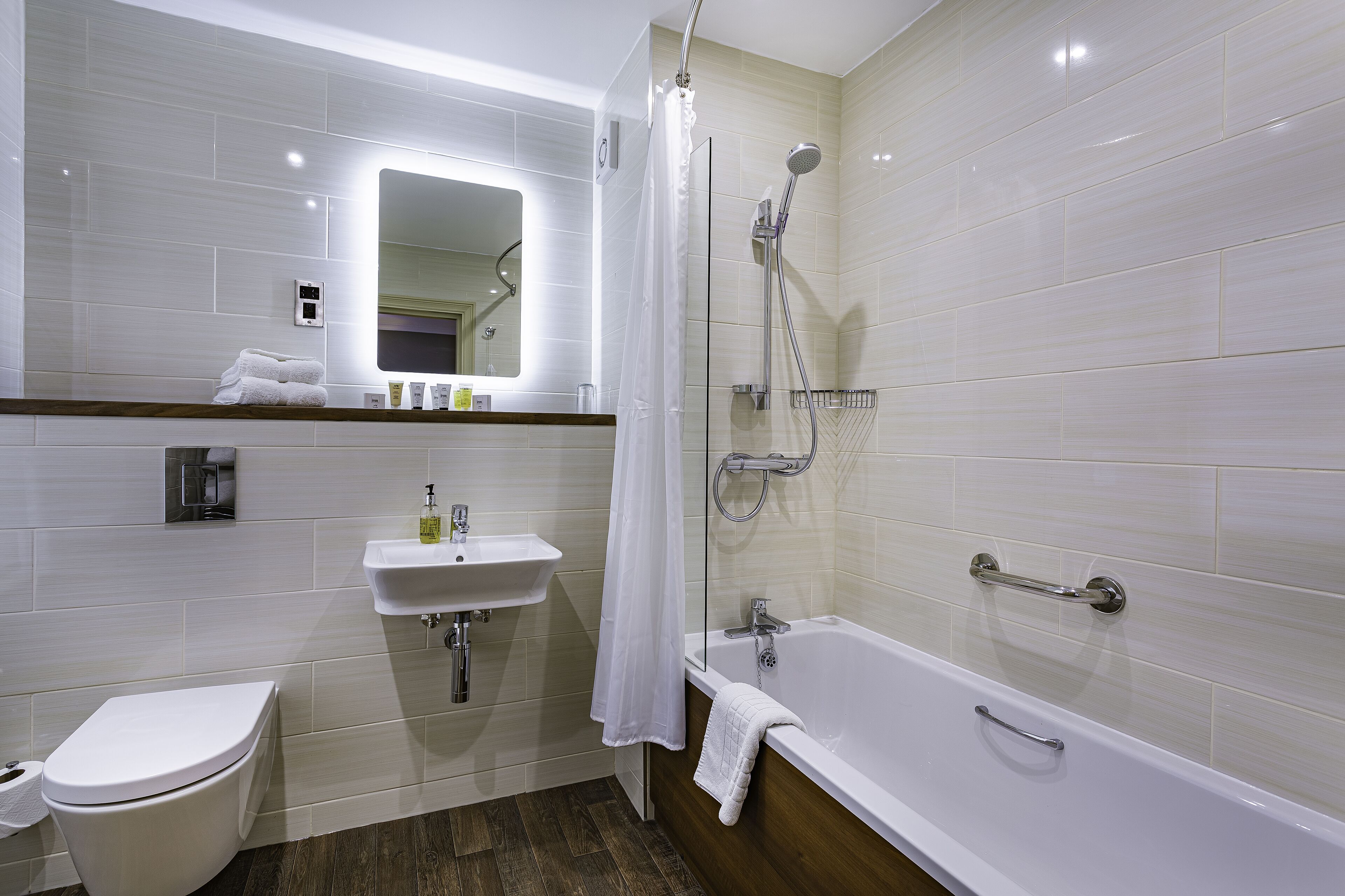 A modern bathroom with a toilet, sink, bathtub, and shower.