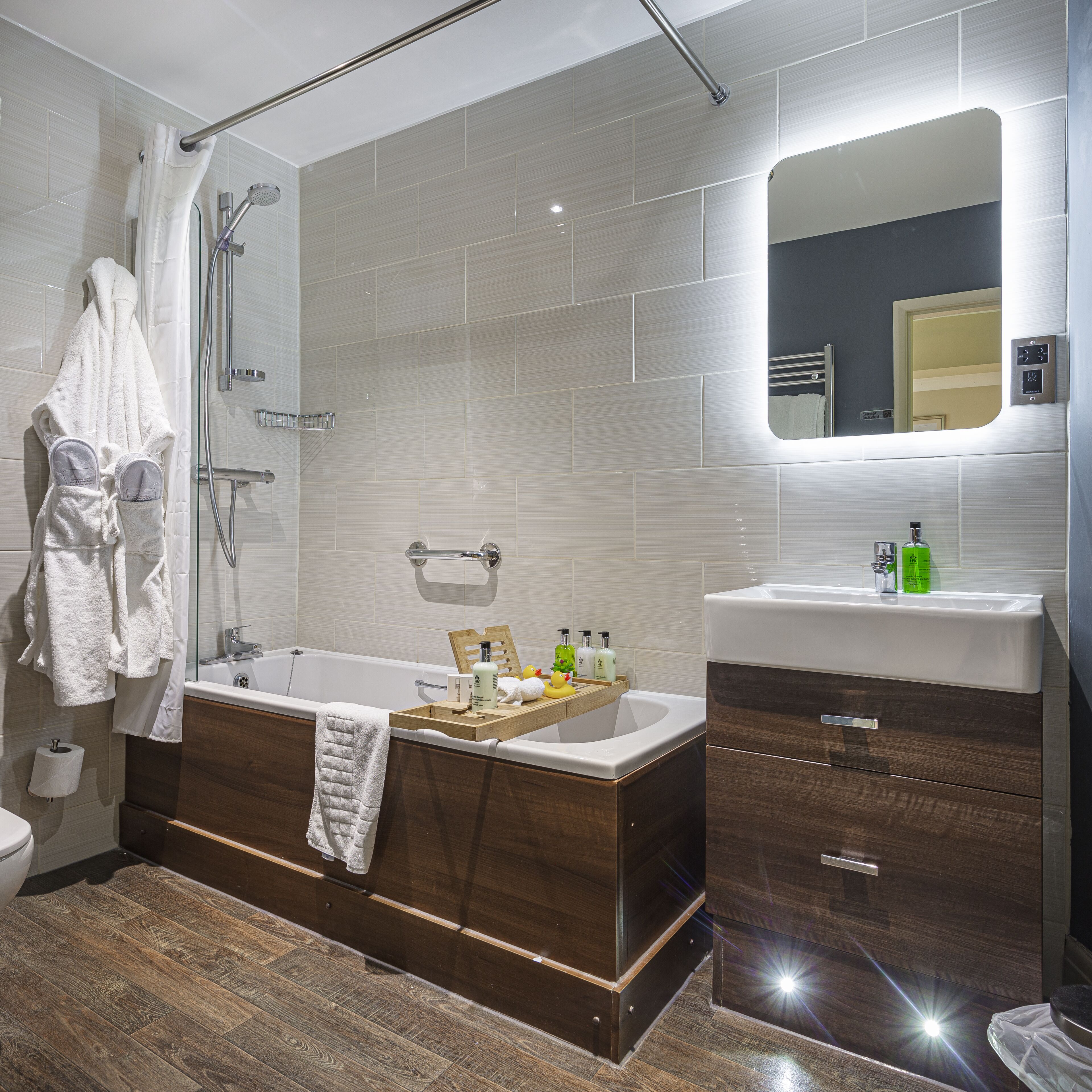 Ein modernes Badezimmer mit einer Badewanne, einem Waschtisch mit Spiegel und einer Duschkabine.