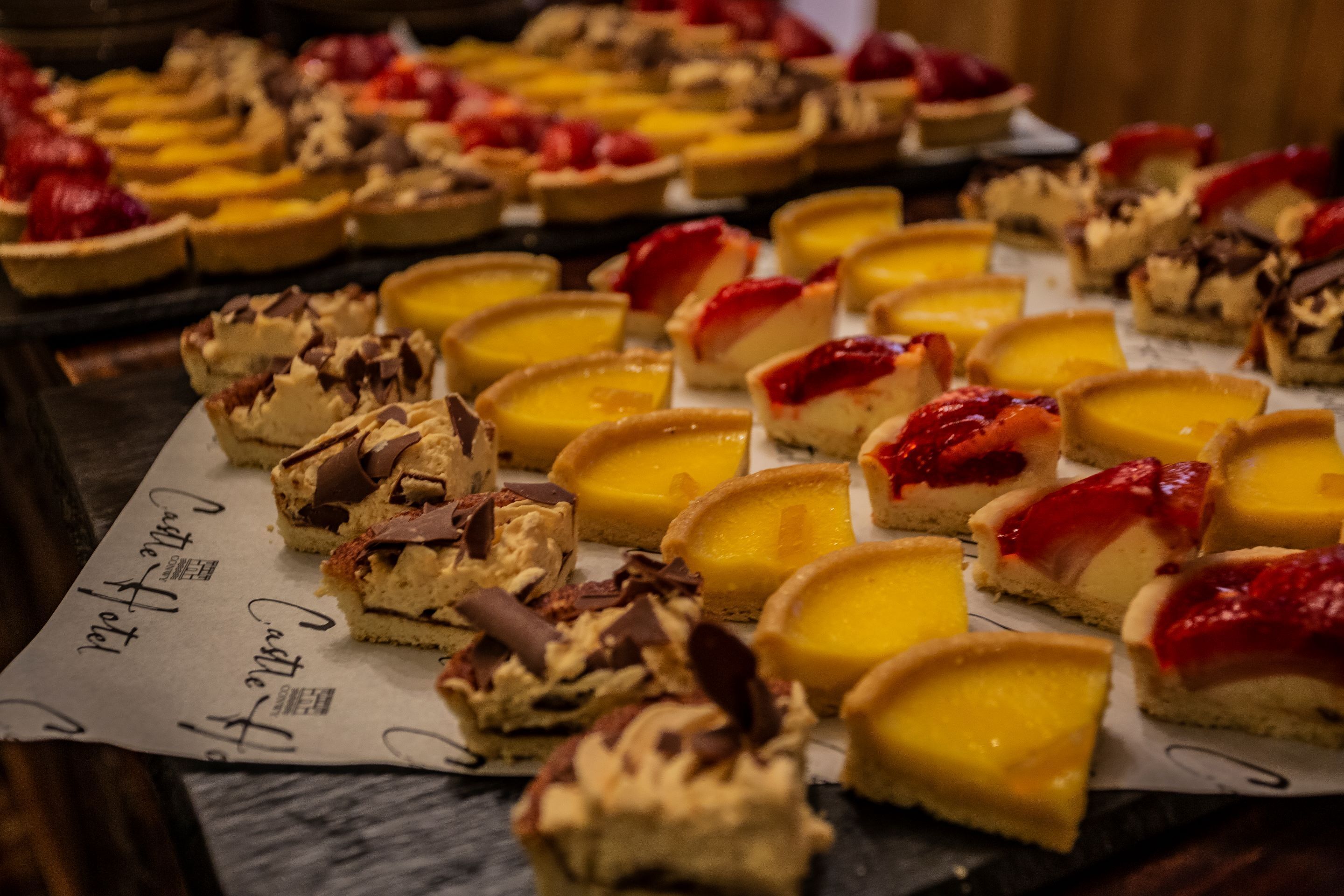 Diversos postres sobre una mesa, como tartas y pasteles a base de crema pastelera.