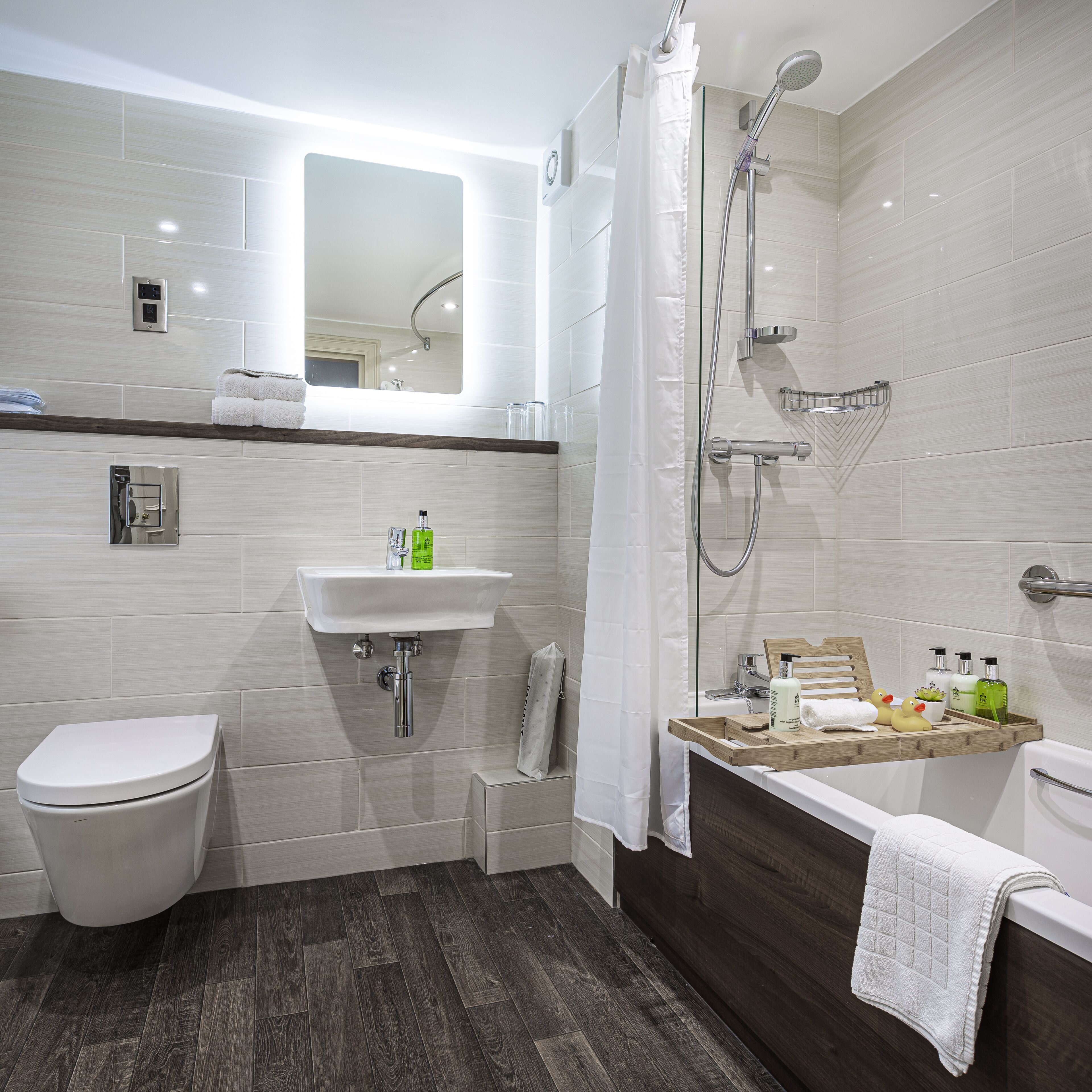 A modern bathroom with a toilet, sink, shower, and bathtub.