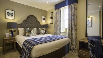 A hotel room with a large bed, two bedside tables, a chair, and a window with curtains.