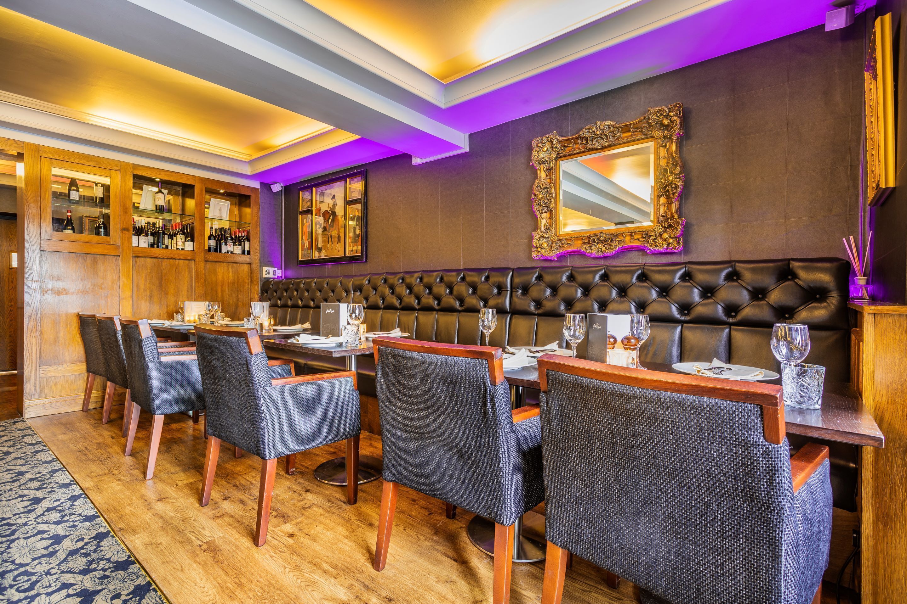 Un restaurante con zona de bar, paneles de madera y una banqueta de cuero capitonada.