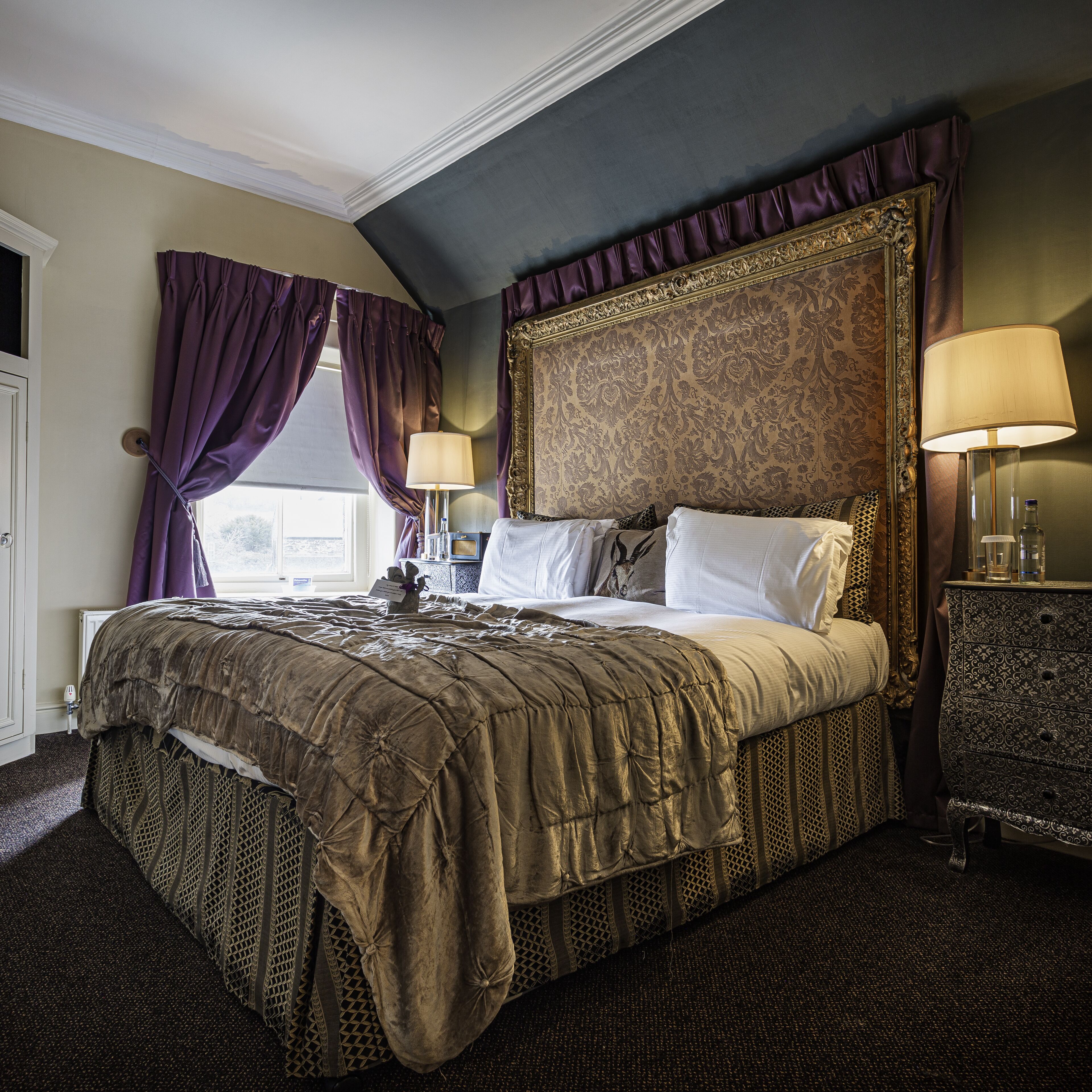 A large bed with a headboard, two bedside lamps, and a nightstand with a lamp.