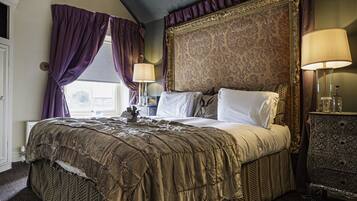A large bed with a headboard, two bedside lamps, and a nightstand with a lamp.