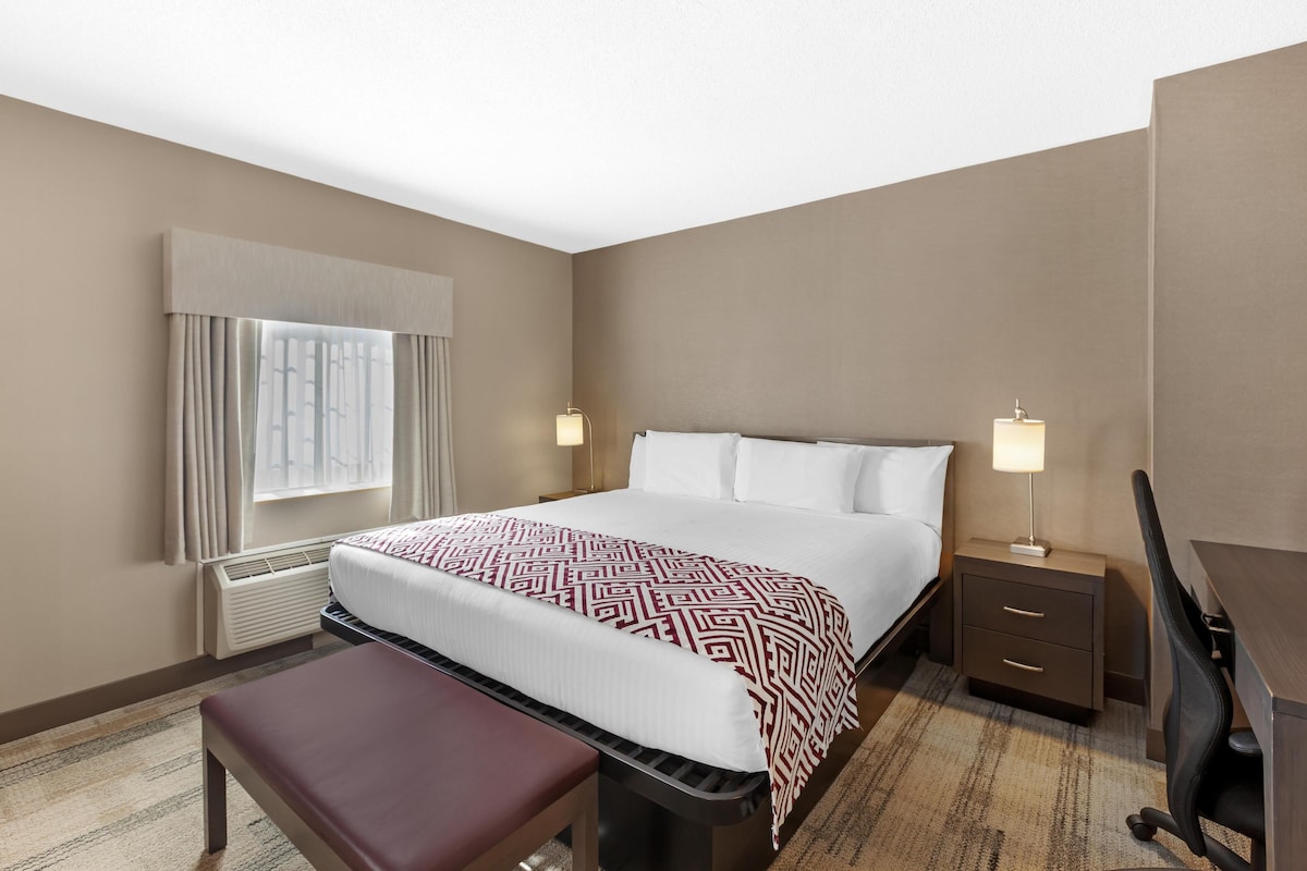 A hotel room with a bed, bedside tables, a desk, and a chair.