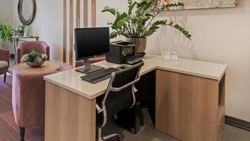 A modern office desk with a computer, printer, and potted plant.