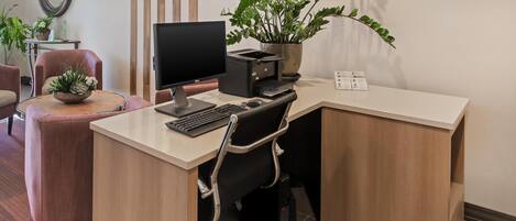 A modern office desk with a computer, printer, and potted plant.