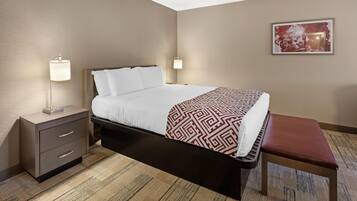 A hotel room with a bed, bedside tables, a bench, and a painting on the wall.
