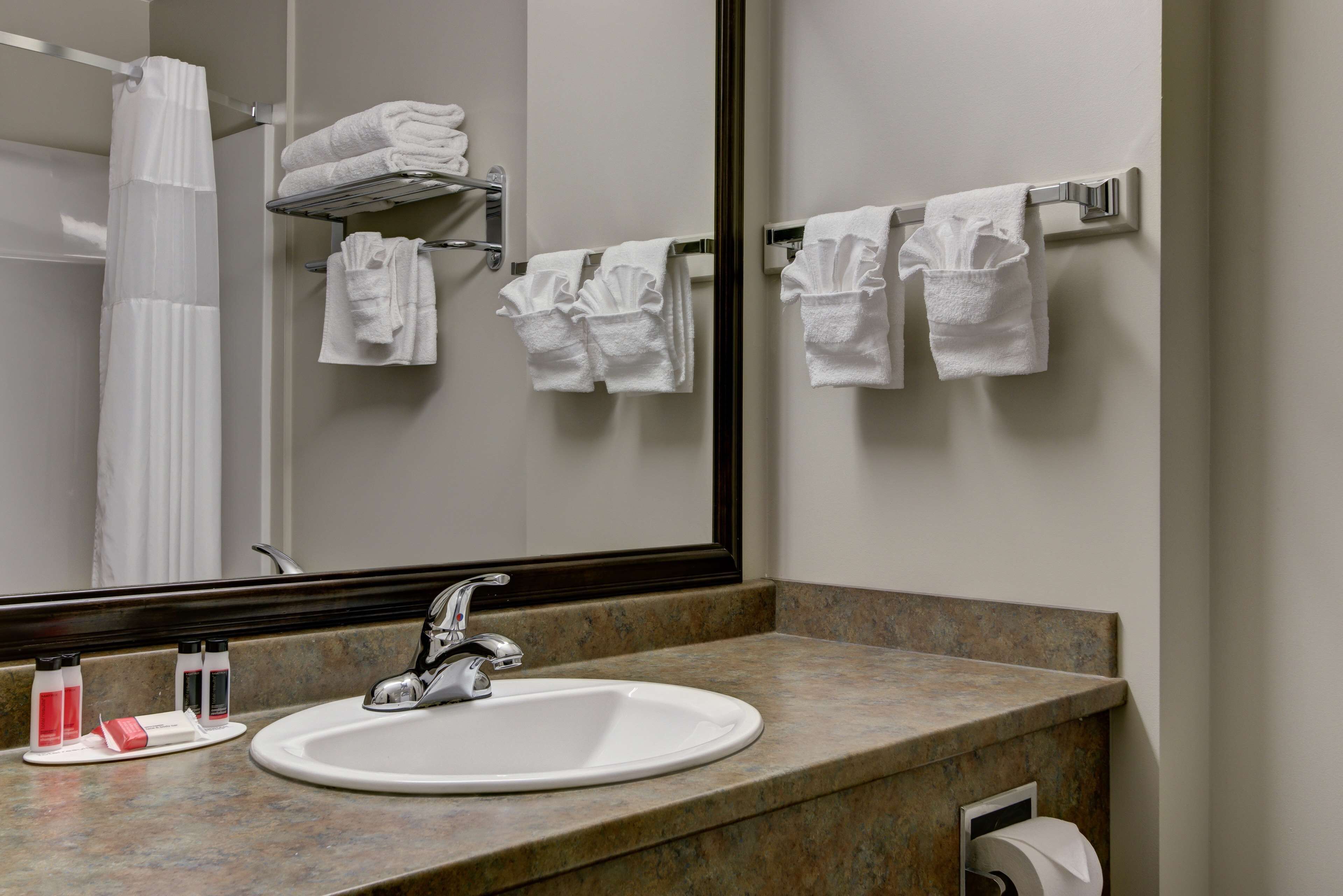 A bathroom with a sink, mirror, towel rack, and a shower curtain.
