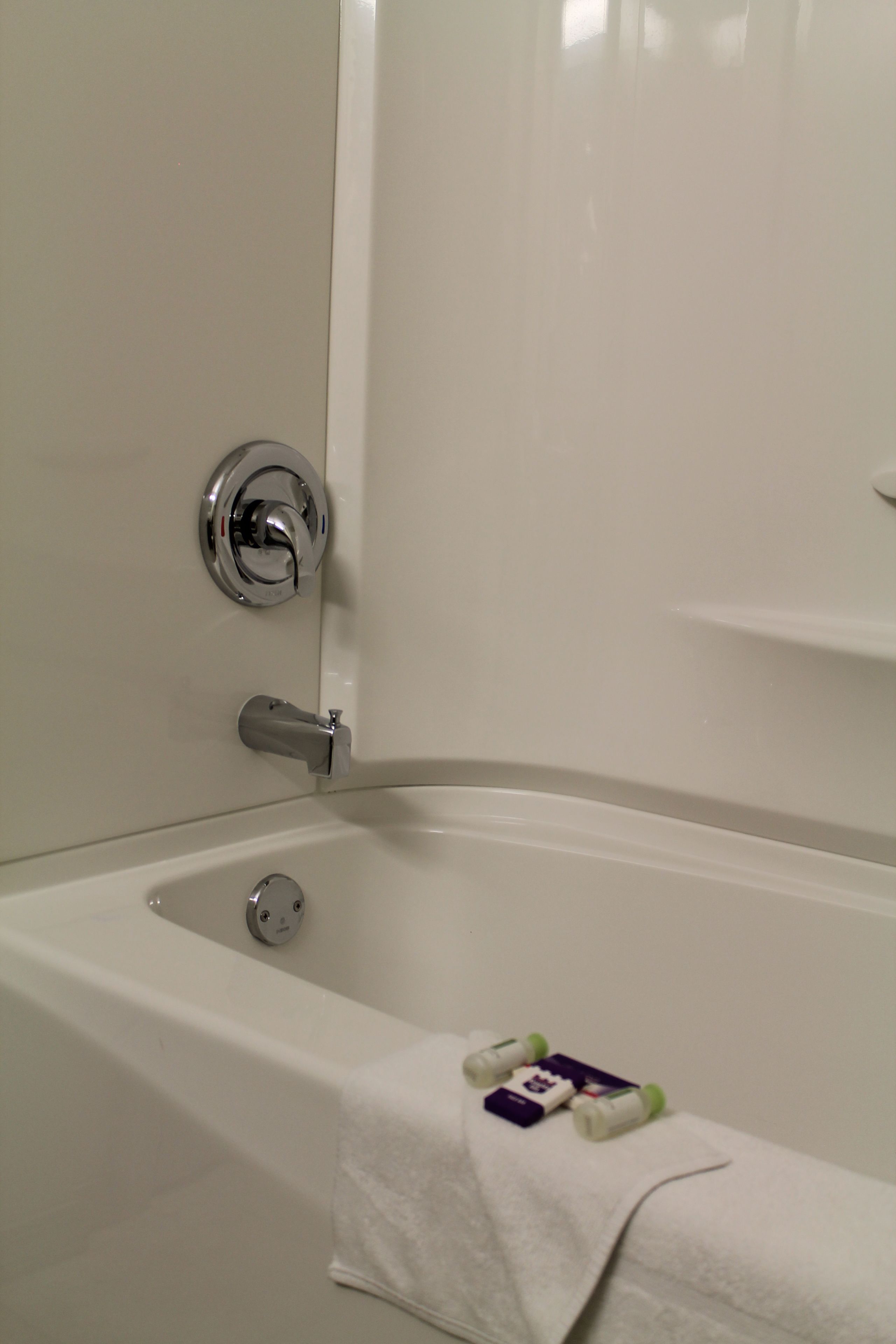 A white bathtub with a chrome faucet and a towel on the side.