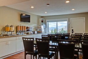 A modern kitchen with white cabinets, a large island with a sink, and a dining area with wooden chairs.