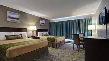 Une chambre d’hôtel avec deux lits, un bureau, une chaise, une télévision et deux lampes.