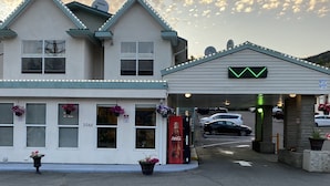 A building with a garage entrance, a Coca-Cola sign, and a green arrow sign. - Sage Inn Merritt (Merritt)