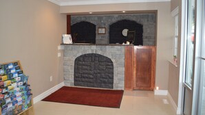 A lobby with a stone fireplace, a wooden reception desk, and a red carpet. - Sage Inn Merritt (Merritt)