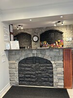 Una chimenea de piedra con un reloj encima, bolsas de aperitivos en la parte superior y un cartel con la hora de registro.