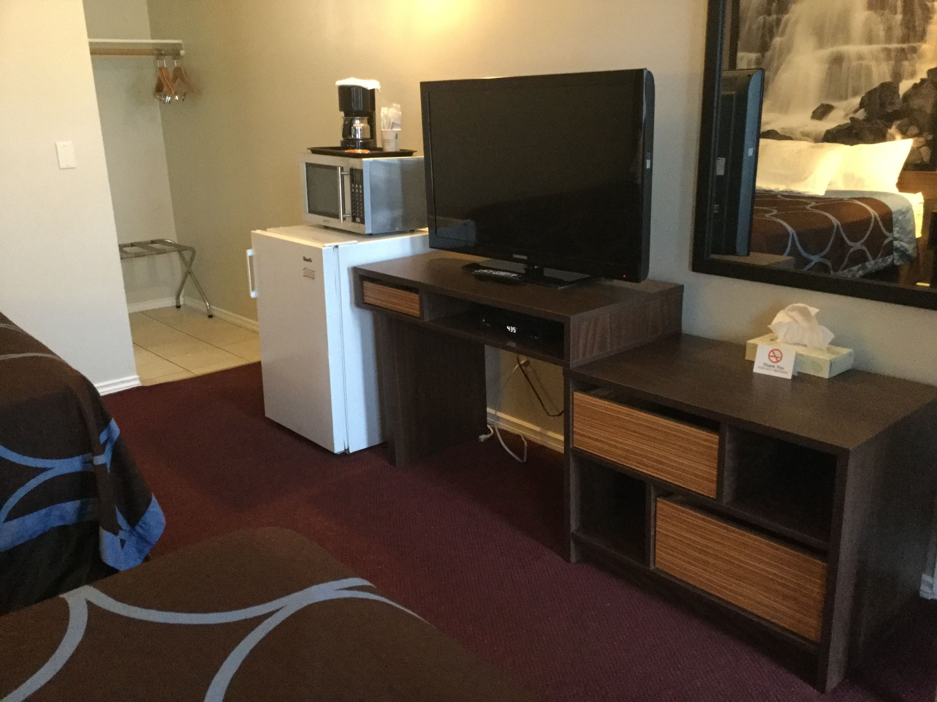 Ett hotellrum med en säng, en tv, en mikrovågsugn och ett kylskåp.