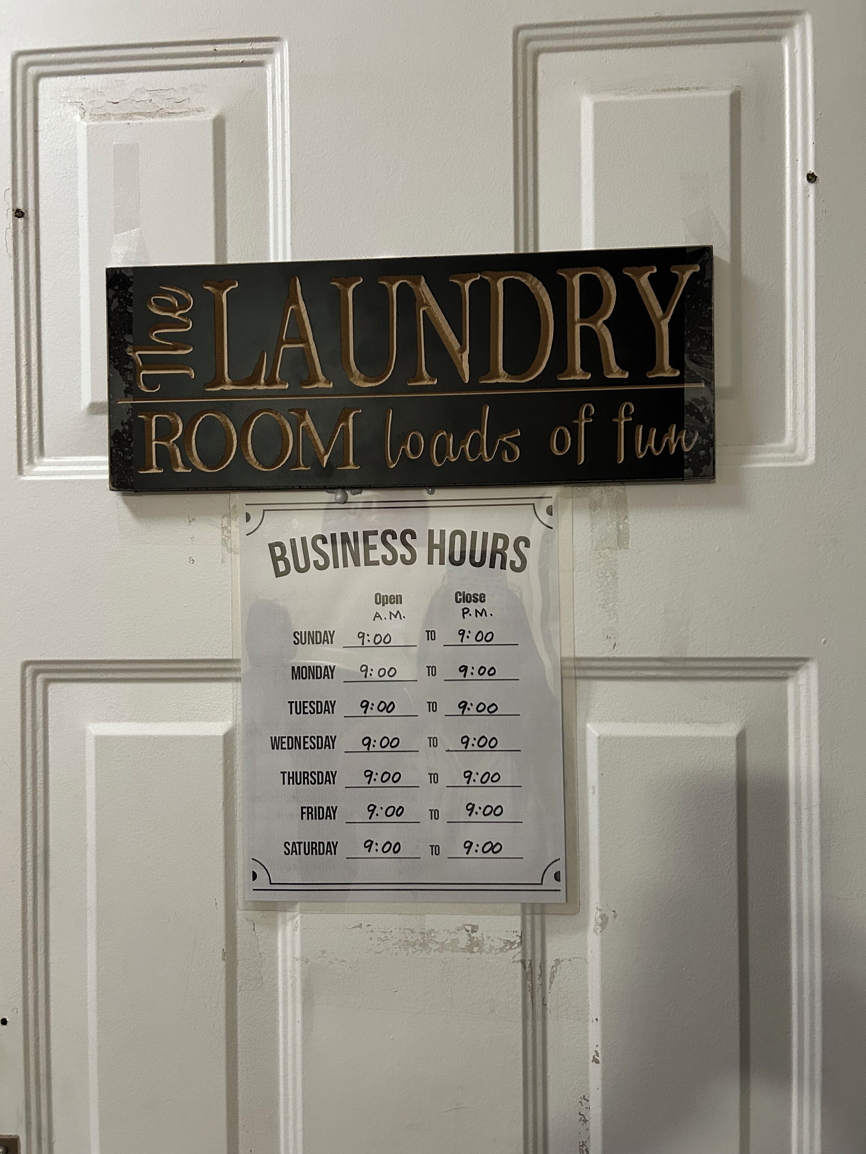 A sign indicating the laundry room's business hours, which are from 9:00 AM to 9:00 PM, Monday through Saturday.