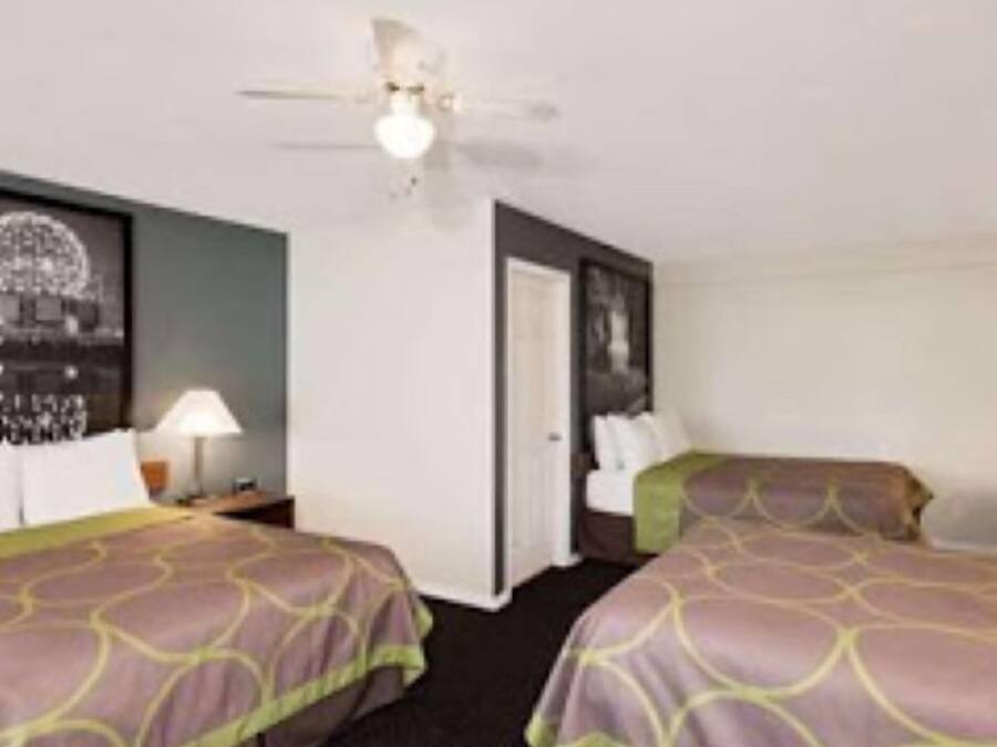 Habitación de hotel con dos camas, ventilador de techo y un cuadro en la pared.