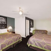 Habitación de hotel con dos camas, ventilador de techo y un cuadro en la pared.