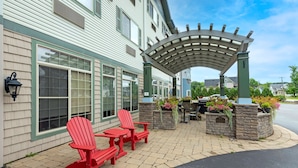 A patio area with Adirondack chairs and a pergola, featuring stone planters with flowers. - Best Western Plus Vineyard Inn & Suites (Penn Yan)
