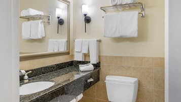 Une salle de bain équipée d’un lavabo, d’un miroir, d’un porte-serviettes et de toilettes.