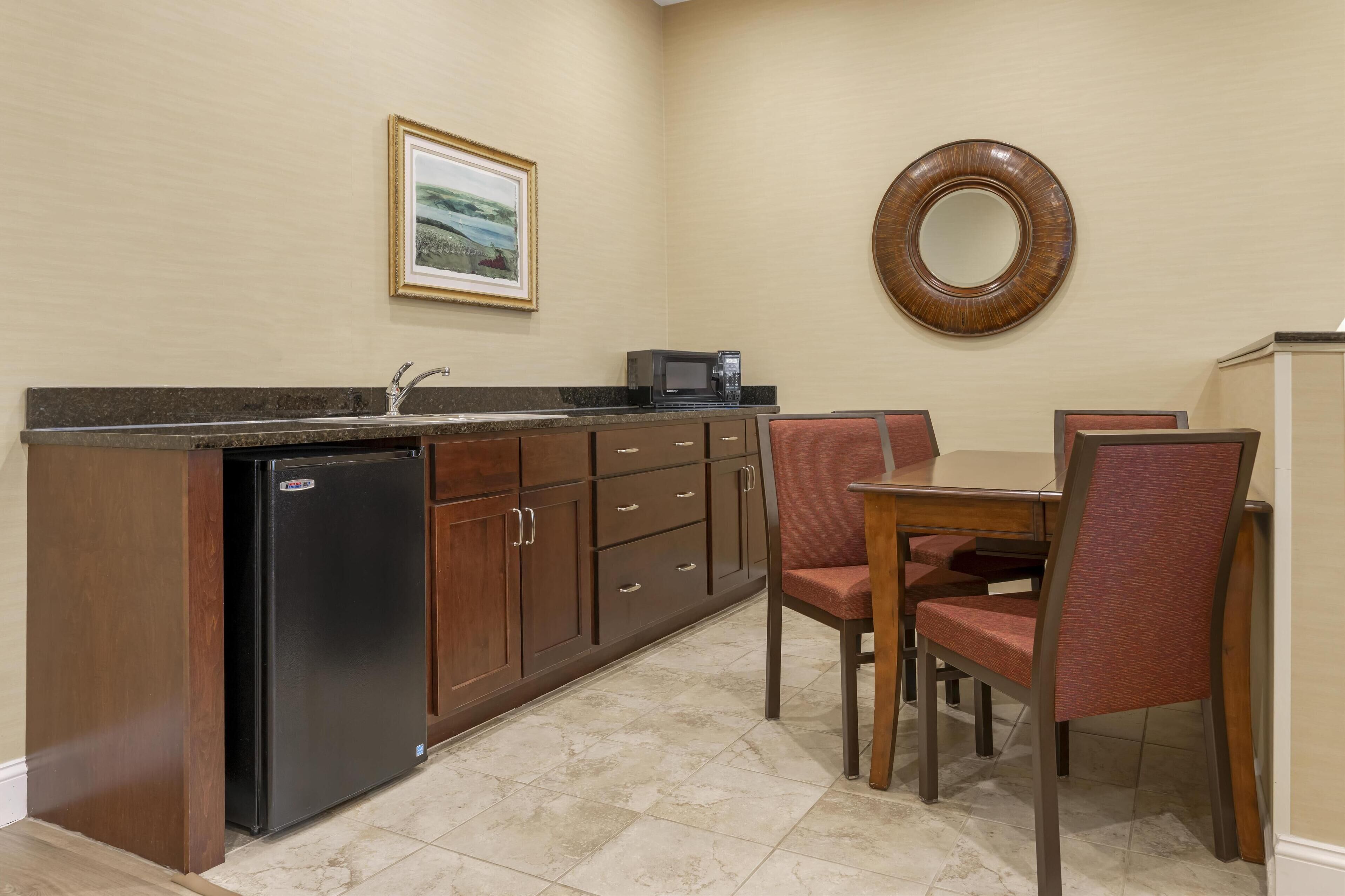 Una cocina compacta con refrigerador, microondas y un comedor con sillas y una mesa.
