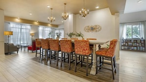 A spacious dining area with a long table and six chairs, a chandelier, and a decorative wall piece. - Best Western Plus Vineyard Inn & Suites (Penn Yan)