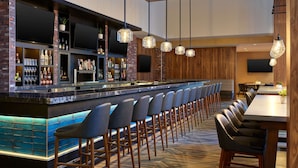 A bar area with a long counter, multiple bar stools, and a variety of bottles and glasses. - Embassy Suites by Hilton Washington D.C. – Convention Center (Washington)