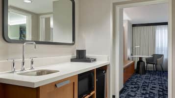 A modern hotel bathroom with a sink, mirror, and a television.