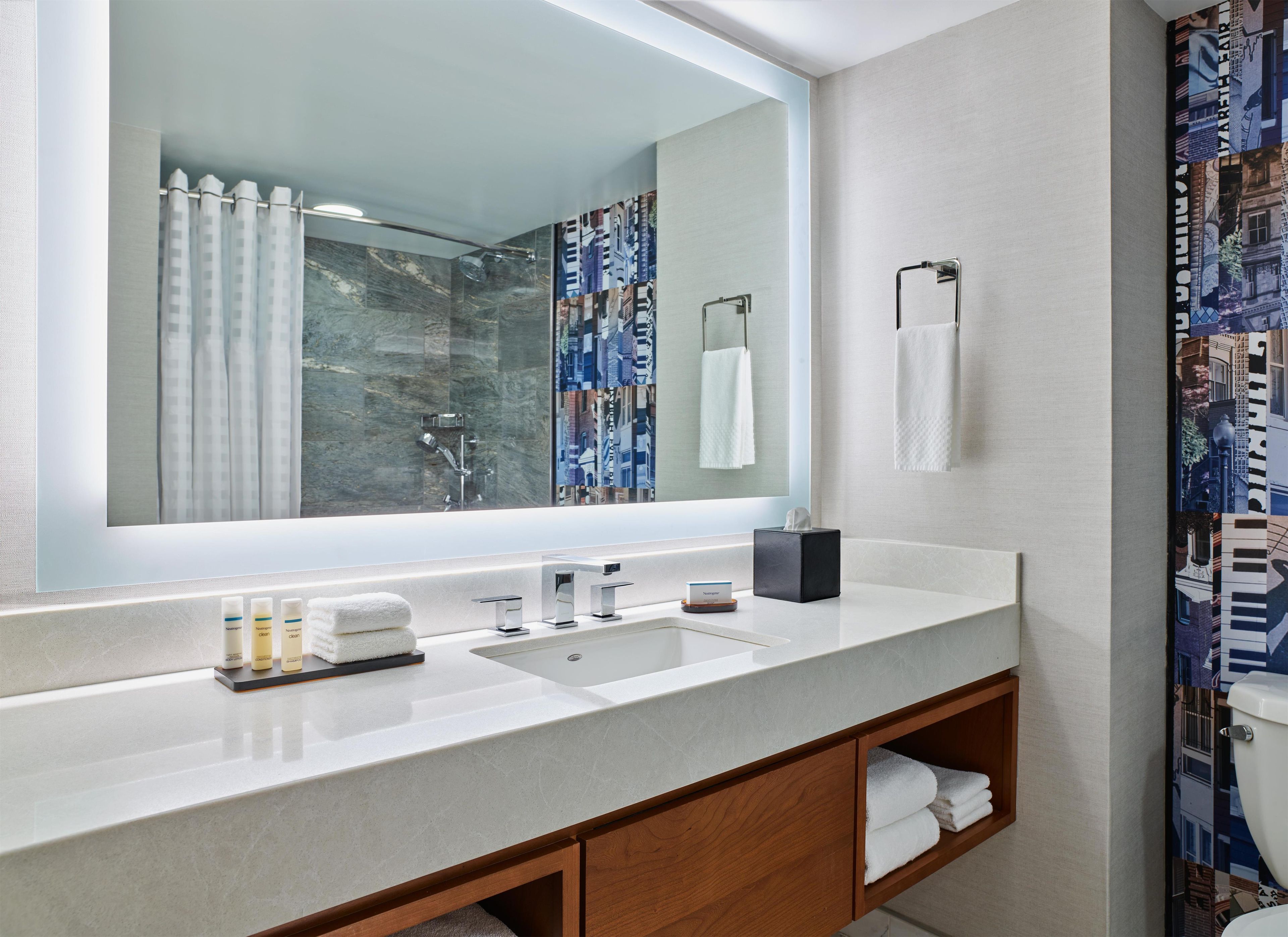 A bathroom with a large mirror, a sink, a towel rack, and a shower curtain.