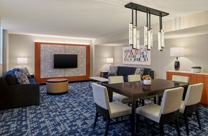 A modern hotel room with a flat-screen TV, a dining area with a table and chairs, and a seating area with sofas and a patterned rug. - Embassy Suites by Hilton Washington D.C. – Convention Center (Washington)