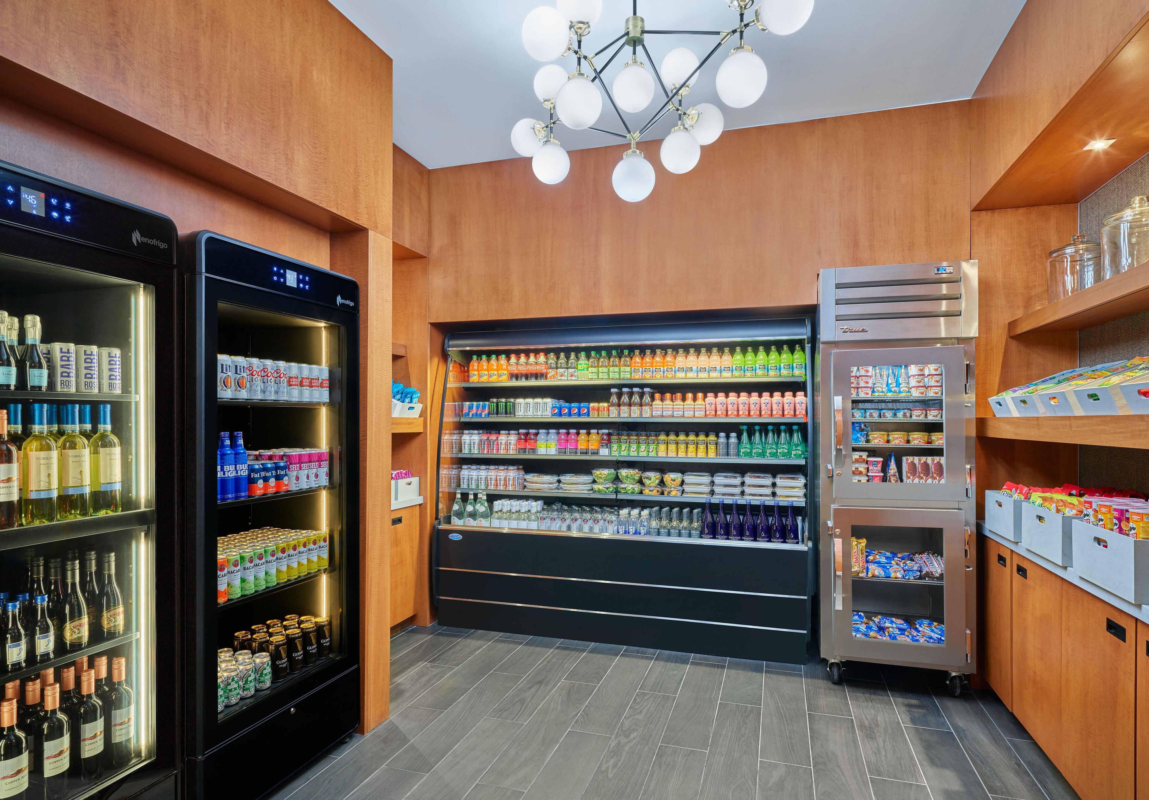 A well-lit beverage kiosk with refrigerated sections for wine and beer, and shelves stocked with various drinks and snacks.