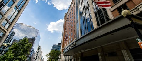Un hôtel doté d’une façade moderne en verre, d’un drapeau et d’une enseigne indiquant qu’il s’agit d’un hôtel Marriott.