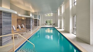 An indoor swimming pool with clear blue water, surrounded by white tiled walls and a few lounge chairs. - Embassy Suites by Hilton Washington D.C. – Convention Center (Washington)