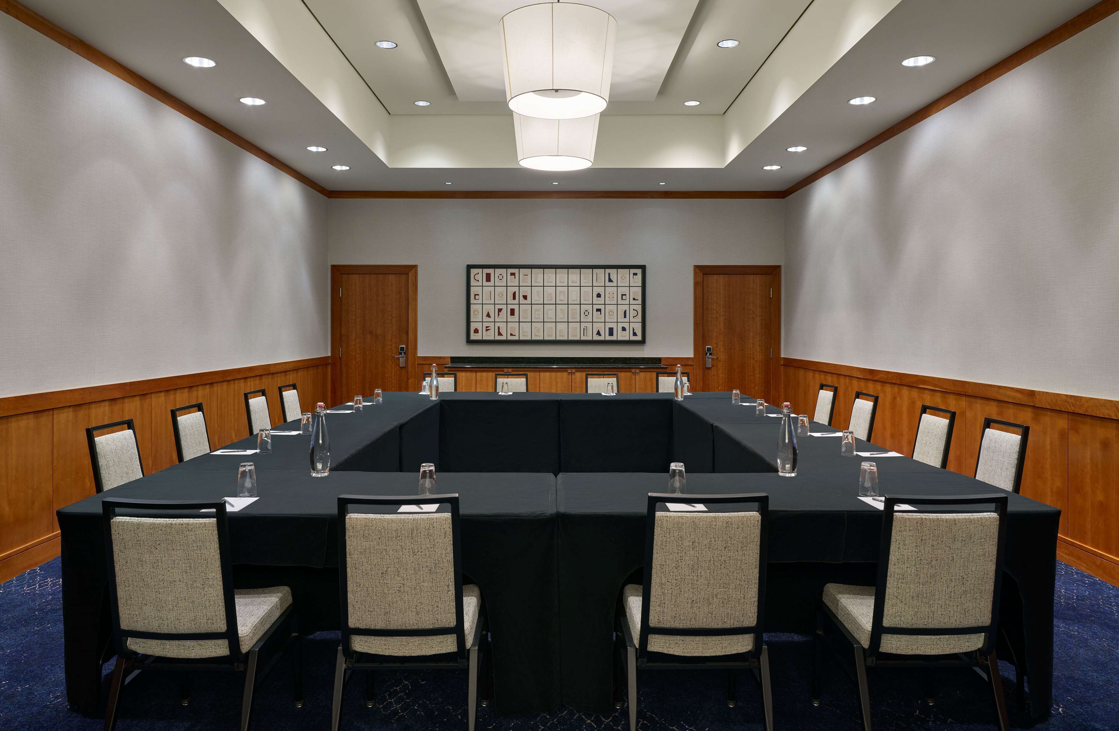 Un salón de conferencias con una larga mesa, sillas y un candelabro.