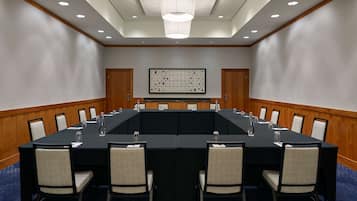 Un salón de conferencias con una larga mesa, sillas y un candelabro.