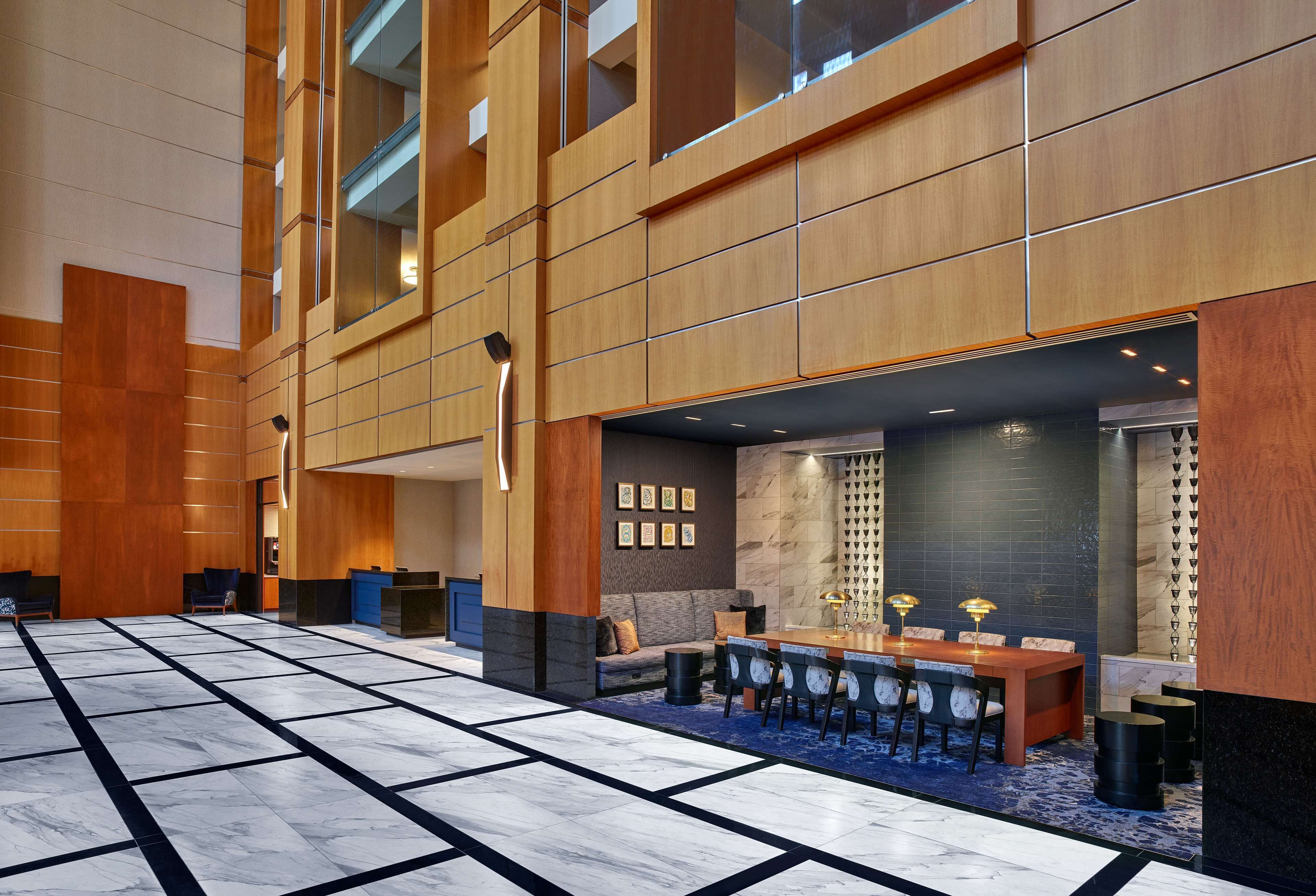 A spacious lobby with a marble floor, a reception desk, a seating area with a sofa and chairs, and a dining area with a table and chairs.