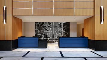 A reception area with a modern design, featuring a large wall with a city map, two reception desks, and a marble floor.