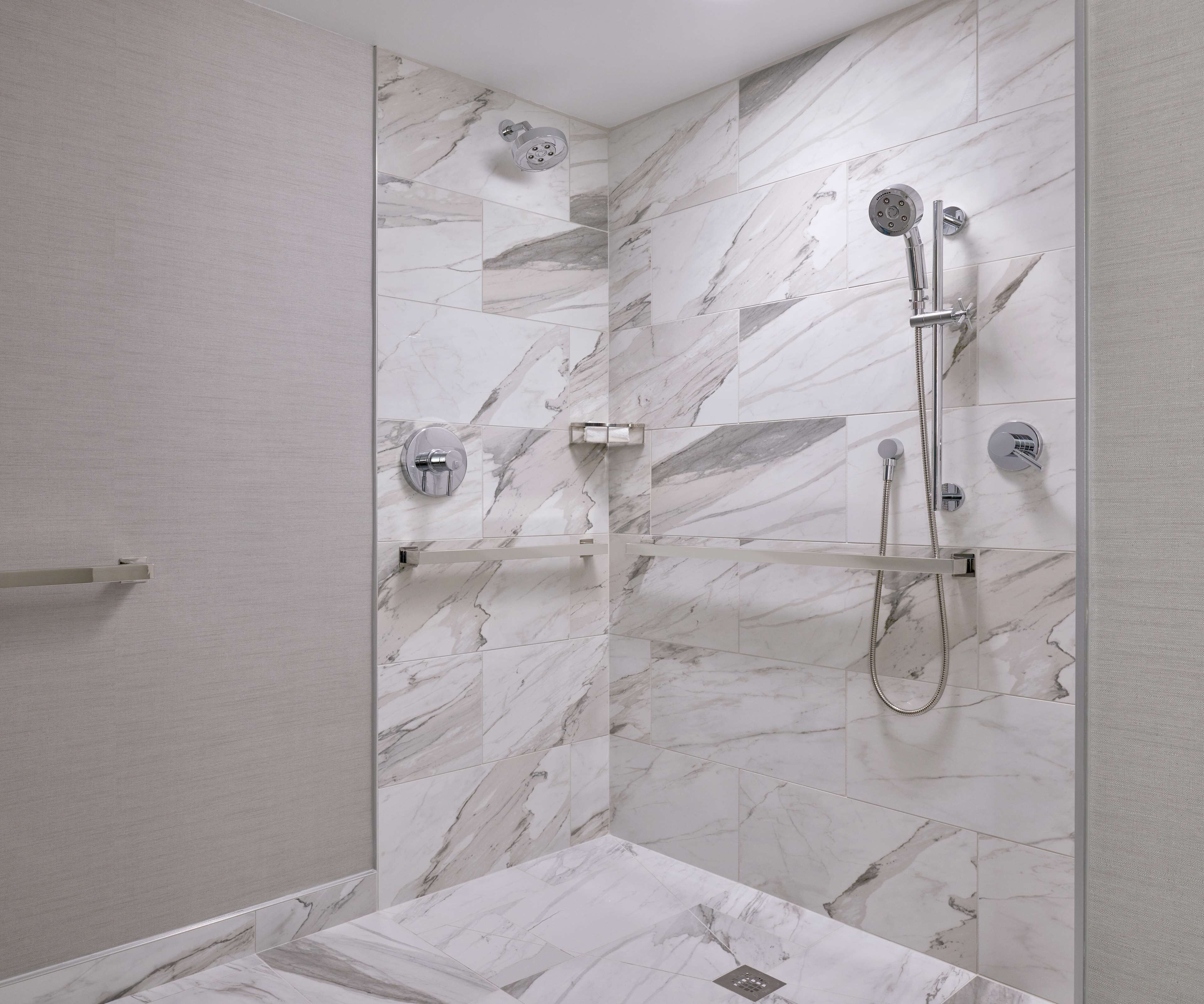 A modern bathroom with a glass shower enclosure, marble tiles, and a built-in towel rack.