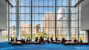 A spacious indoor area with a high ceiling and large windows, offering views of tall buildings and a clear sky. - Hilton Garden Inn Houston/Galleria Area (Houston)