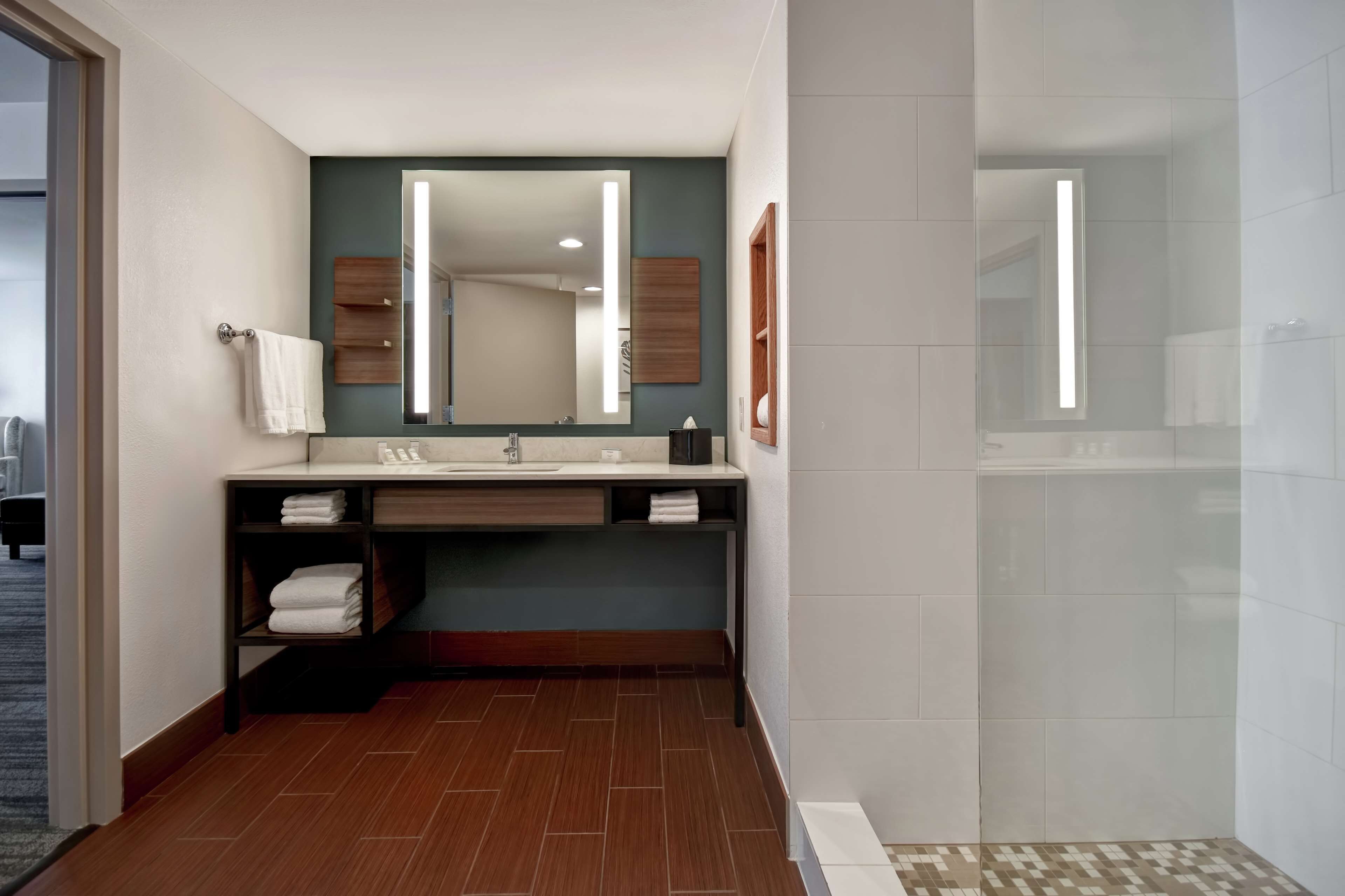A modern bathroom with a large mirror, a sink, and a shower area.