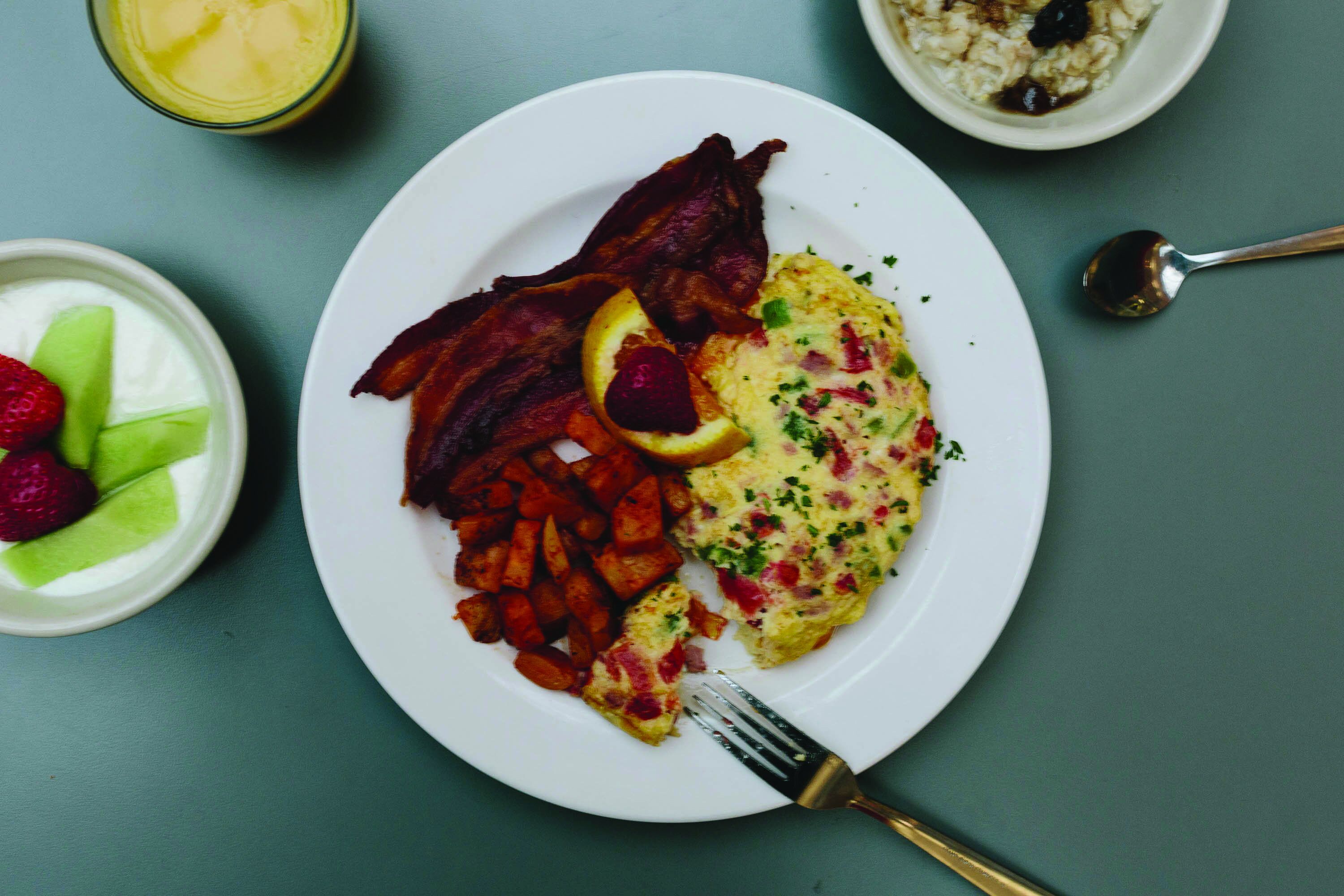 Un plato de comida con tocino, huevos y papas.