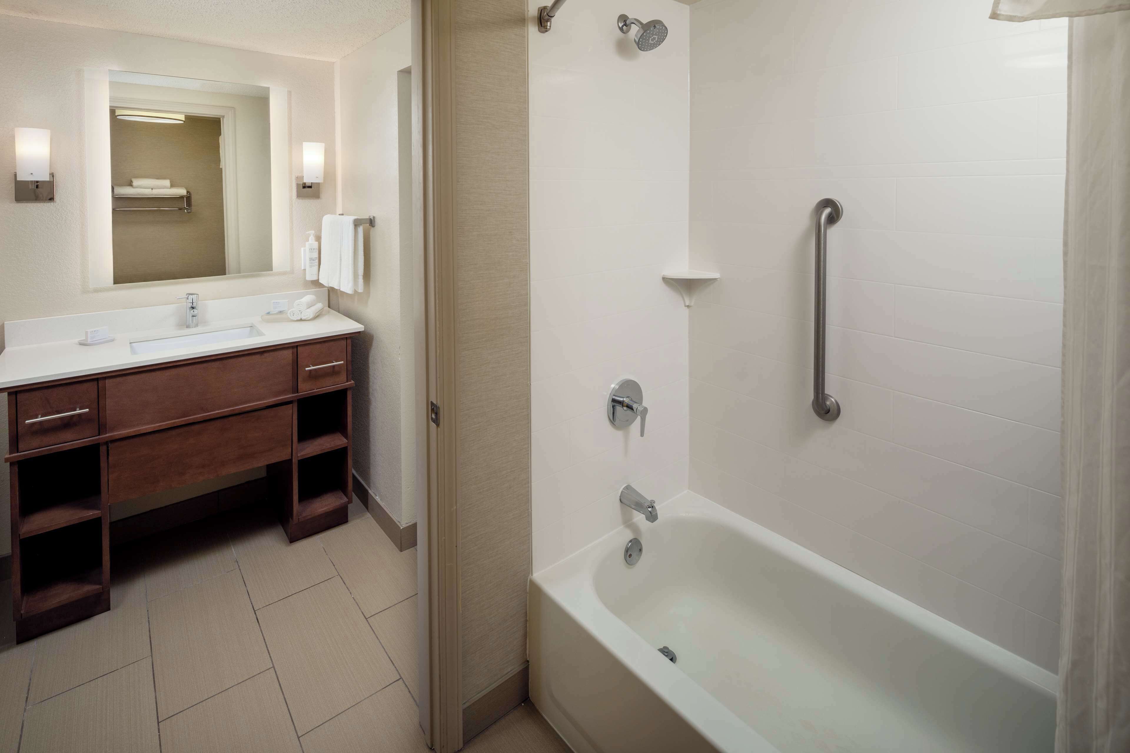 A modern bathroom with a white sink, vanity, and bathtub.