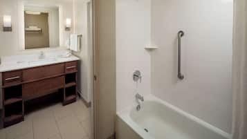 Un baño moderno con lavamanos, tocador y bañera blancos.