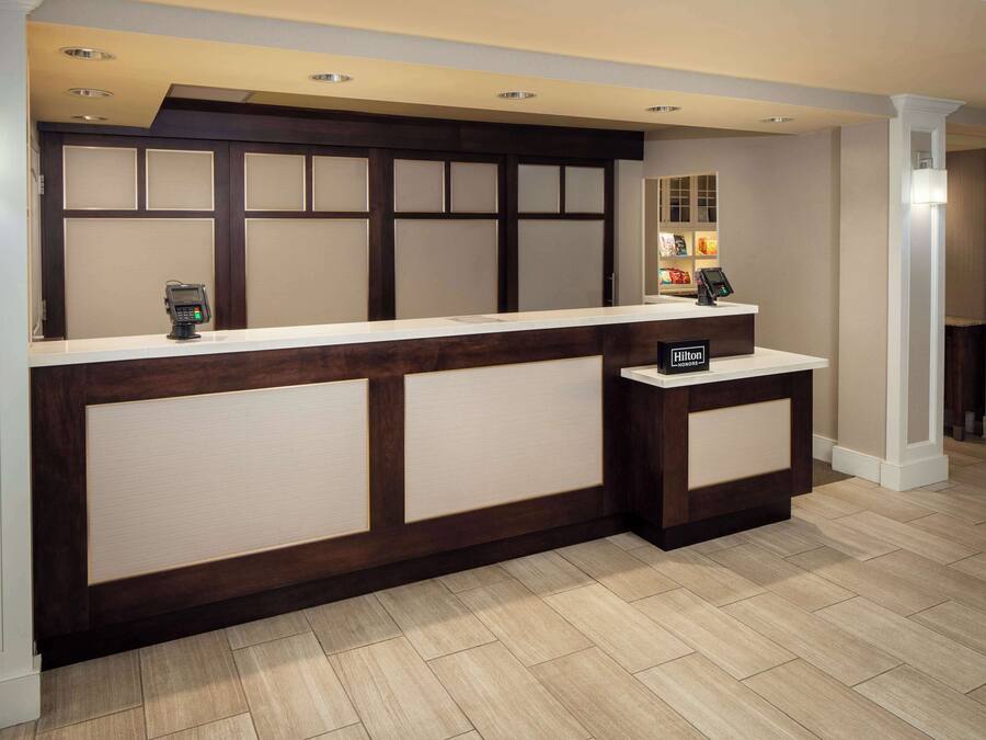 A reception desk with a modern design, featuring a wooden panel and a white counter.