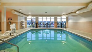 Une piscine intérieure à l’eau claire, entourée de baies vitrées et équipée de dispositifs de sécurité.
