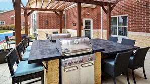 Une terrasse extérieure équipée d’un barbecue, d’une table à manger et de chaises.