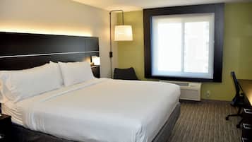 Habitación de hotel con una cama grande, un escritorio, una silla, una lámpara y una ventana.